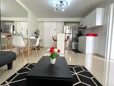 a living room with a black table and a kitchen at Departamento con vista de Lima in Lima