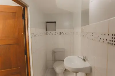 a white bathroom with a toilet and a sink at Lucios Cusco in Cusco