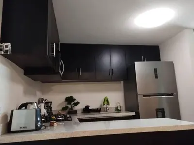 a kitchen with black cabinets and a refrigerator at Mini Apartamento, cerca al Malecón de Chorrillos in Lima