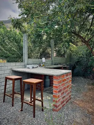 a table and two stools next to a brick grill at Amaya Experience in Miraflores