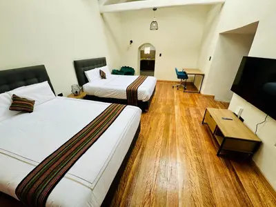 a hotel room with two beds and a desk at Way Kap Hostel Cusco in Cusco