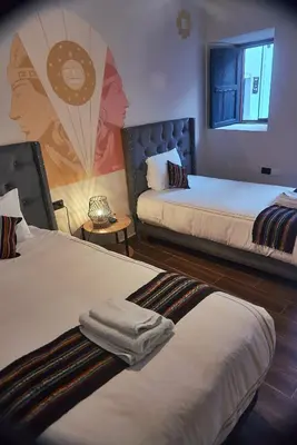a room with two beds and a painting on the wall at Way Kap Hostel Cusco in Cusco