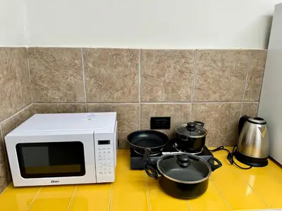 a microwave and two pots and pans on a stove at Way Kap Hostel Cusco in Cusco