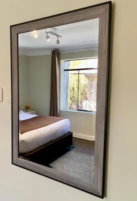a mirror reflecting a bedroom with a bed and a window at Casa Pardo in Cusco