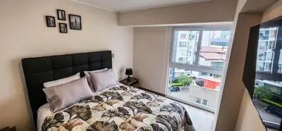 a bedroom with a bed and a large window at Departamento de Estreno en Miraflores in Lima