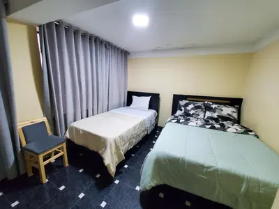 a hotel room with two beds and a chair at Jebas House in Cusco