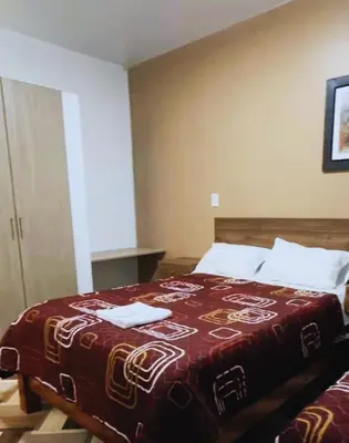a bedroom with a bed with a red blanket on it at Hospedaje Mónaco - Jauja Airport in Jauja