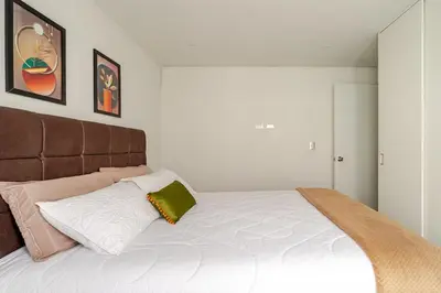 a white bed with a brown headboard in a bedroom at Vacation Escape - Elegant Barranco Stay near Beach & Art in Lima
