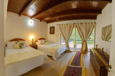 a bedroom with two beds and a large window at La Casita de Orfi in Calca