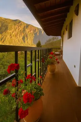a balcony with red flowers and a view of a mountain at La Casita de Orfi in Calca