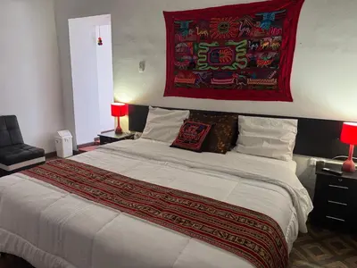a bedroom with a large bed with a red tapestry above it at Mallku Wasi - Lodging Hotel Cusco in Cusco
