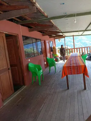 a porch with green chairs and a table and a person at Lucmabamba Dulcesueños Xiomara in Sahuayacu