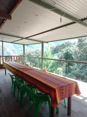 a large table with green chairs and a large window at Lucmabamba Dulcesueños Xiomara in Sahuayacu