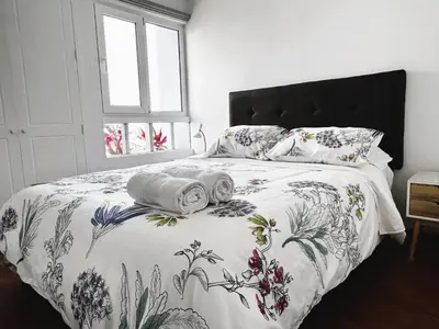 a bedroom with a bed with a floral bedspread and pillows at Excelente ubicación, vista al mar, cerca a Costa 21 in Lima