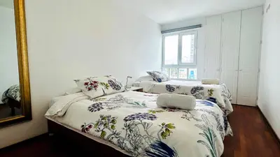 a bedroom with two beds with floral sheets and a mirror at Excelente ubicación, vista al mar, cerca a Costa 21 in Lima