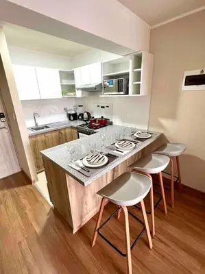 a kitchen with a counter and four stools in it at Departamento estrenó céntrico a universidades in Lima