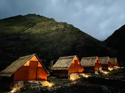 a group of huts with a mountain in the background at SORAYPAMPA - Cabañas Andinas Mamá Andrea Eco Lodge in Soray