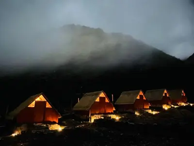 a group of huts in a field with a mountain at SORAYPAMPA - Cabañas Andinas Mamá Andrea Eco Lodge in Soray