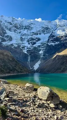 a lake with snow covered mountains in the background at SORAYPAMPA - Cabañas Andinas Mamá Andrea Eco Lodge in Soray