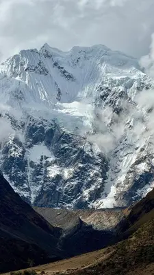 a snow covered mountain with clouds in front of it at SORAYPAMPA - Cabañas Andinas Mamá Andrea Eco Lodge in Soray