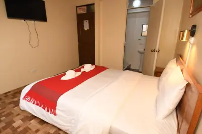 a bedroom with a bed with a red and white blanket at Casa Medina Hostal in Cusco