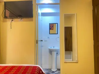 a bathroom with a sink and a toilet and a television at Casa Medina Hostal in Cusco
