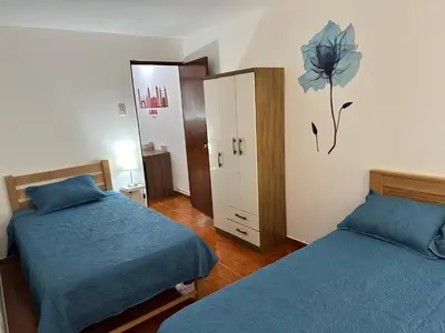 a bedroom with two beds and a dresser with a flower on the wall at Bello depa San Miguel 3 camas 2 tv smart terraza in Lima