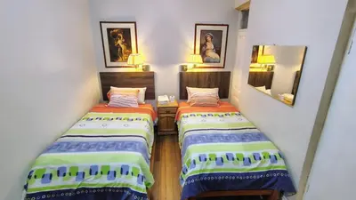 two twin beds in a room with two mirrors at Hospedaje CASA REAL in Huancayo