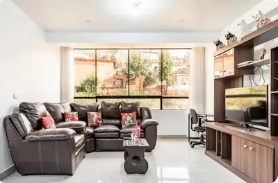 a living room with a leather couch and a television at Casa Monacó in Cusco