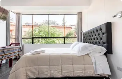 a bedroom with a large bed with a large window at Casa Monacó in Cusco
