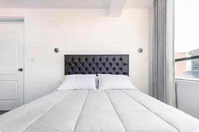 a bedroom with a large white bed with a black headboard at Casa Monacó in Cusco