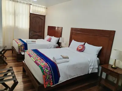 two beds in a room with white walls and wooden floors at NUNA SUMAQ Hotel in Ollantaytambo