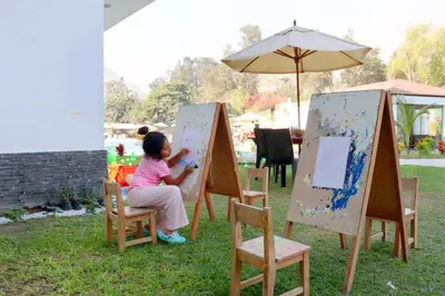 a little girl is painting a painting on a canvas at Ribera del Rio Club Resort in Cieneguilla