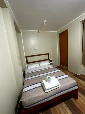 a bedroom with a bed with a towel and a cup on it at Hotel Eli House in Nazca