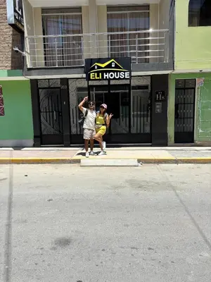 two people sitting on the sidewalk in front of a building at Hotel Eli House in Nazca