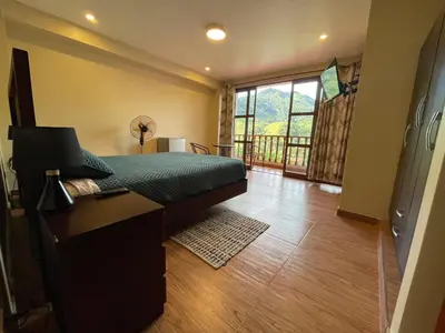 a bedroom with a bed and a desk and a window at MONTEVERDIA - Hotel & Resort in Pozuzo