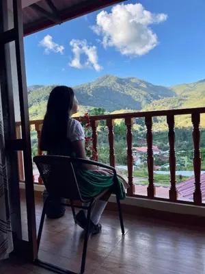 a woman sitting in a chair looking out of a window at MONTEVERDIA - Hotel & Resort in Pozuzo