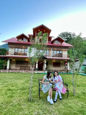 two girls sitting on a bench in front of a house at MONTEVERDIA - Hotel & Resort in Pozuzo