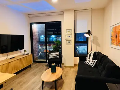 a living room with a black couch and a flat screen tv at MONTERRICO POLO APARTS #17 - Dpto de estreno con Balcón Frente Embajada USA in Lima