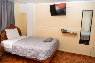 a bedroom with a bed and a television on the wall at Conquistador Hotel in Cusco