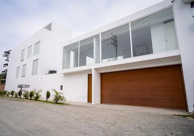 a white house with a brown garage door at CA3 - Casa de Lujo, Fiesta y Piscina - Punta hermosa in Punta Hermosa