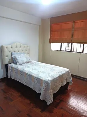 a bedroom with a bed with a blanket and two windows at Alojamientos Perú II in Lima