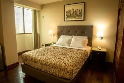 a bedroom with a bed and two lamps and a window at Hotel Lexus in Lima