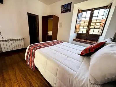 a bedroom with a large white bed and a window at Encanto de Concevidayoc in Cusco