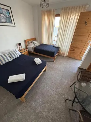 a bedroom with two beds and a chair in it at Ravenala Paracas Hostel & Apartment in Paracas