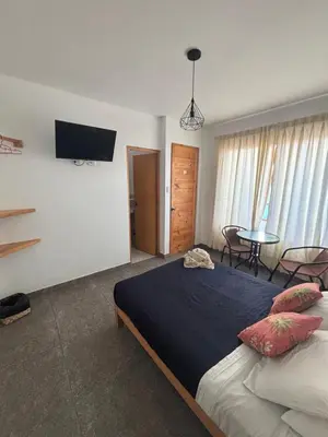 a bedroom with a bed and a tv on the wall at Ravenala Paracas Hostel & Apartment in Paracas