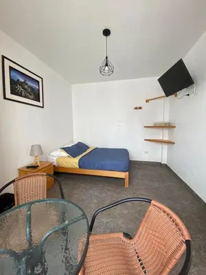 a bedroom with a bed and a glass table and chairs at Ravenala Paracas Hostel & Apartment in Paracas