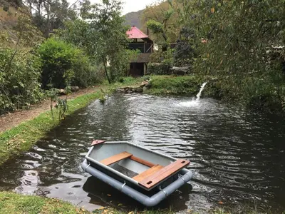 a small boat on a river with a house at HOSTEL INKA PACCHA - cascada inka in Ollantaytambo
