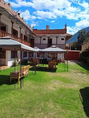 a patio with tables and umbrellas in front of a building at Sequeiros Garden in Ollantaytambo
