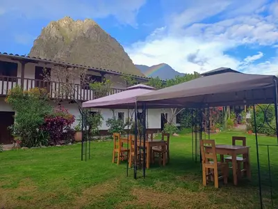 a table and chairs under an umbrella in front of a building at Sequeiros Garden in Ollantaytambo
